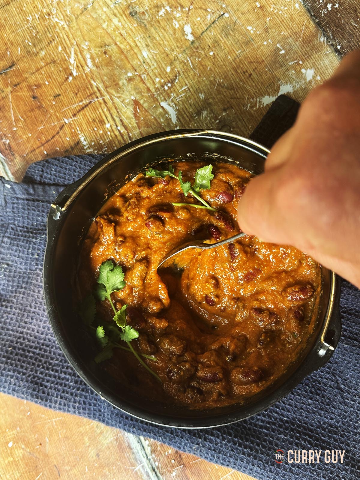 Stirring the kidney bean curry at the table to serve.