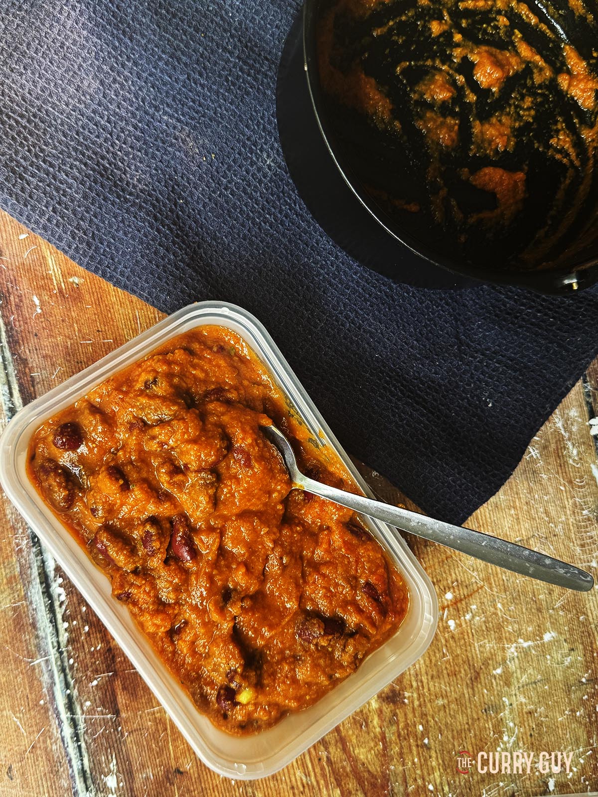 Spooning the kidney bean curry into a plastic container for later.
