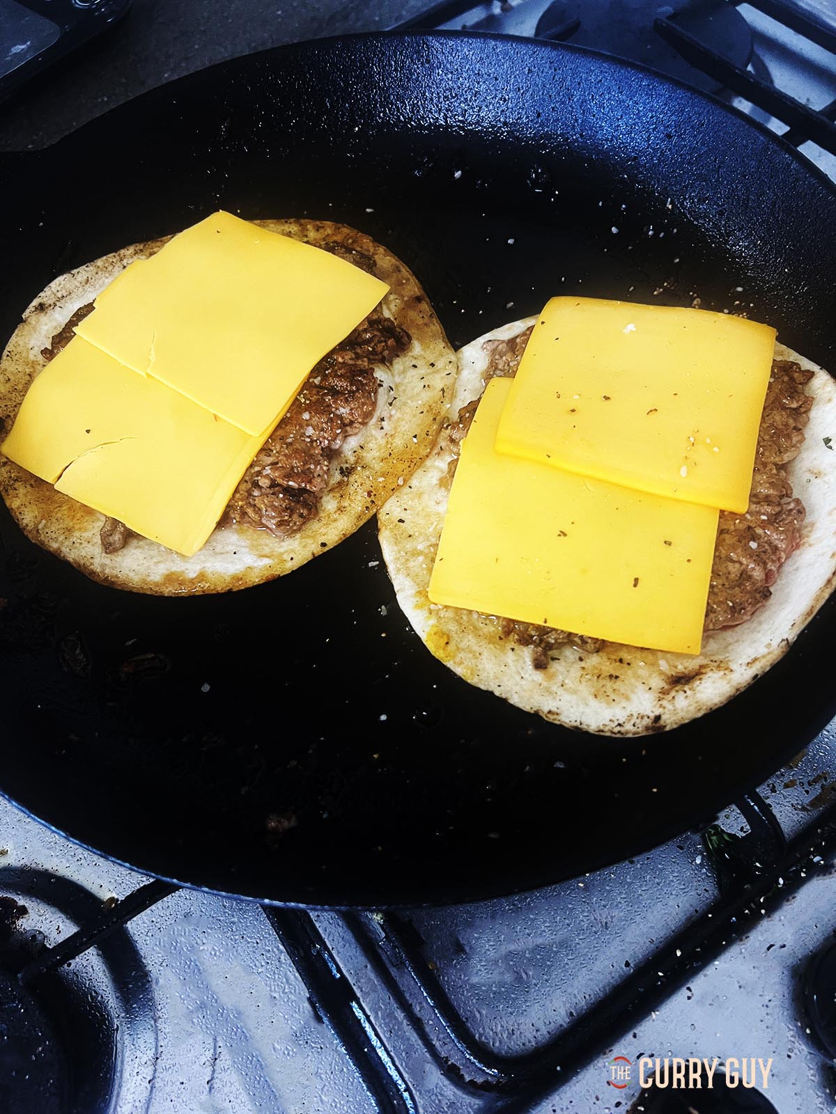 Adding cheese slices to the meat and tortillas.