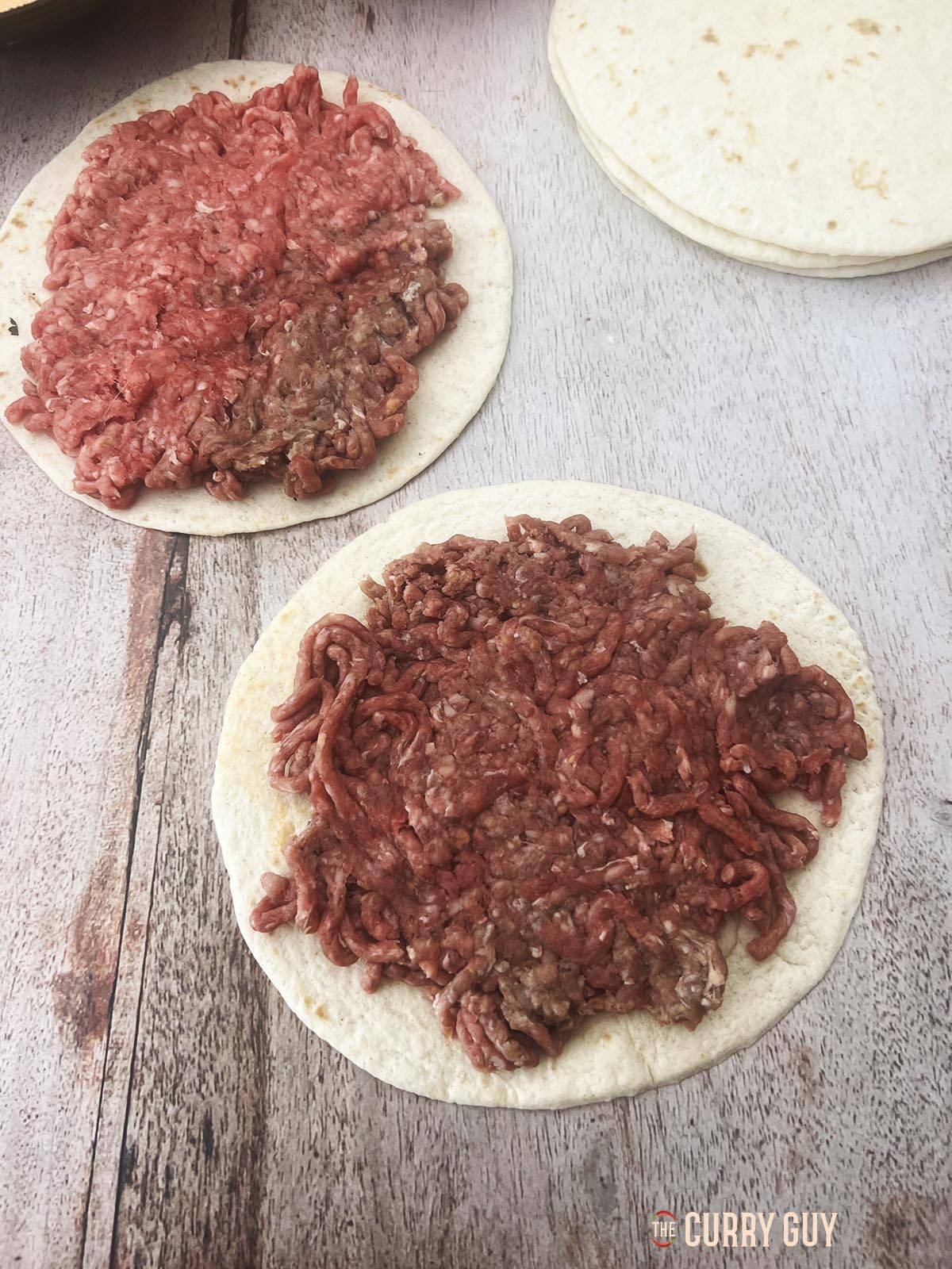 Dividing the meat between the six tortilla and spreading it out over the tortillas.