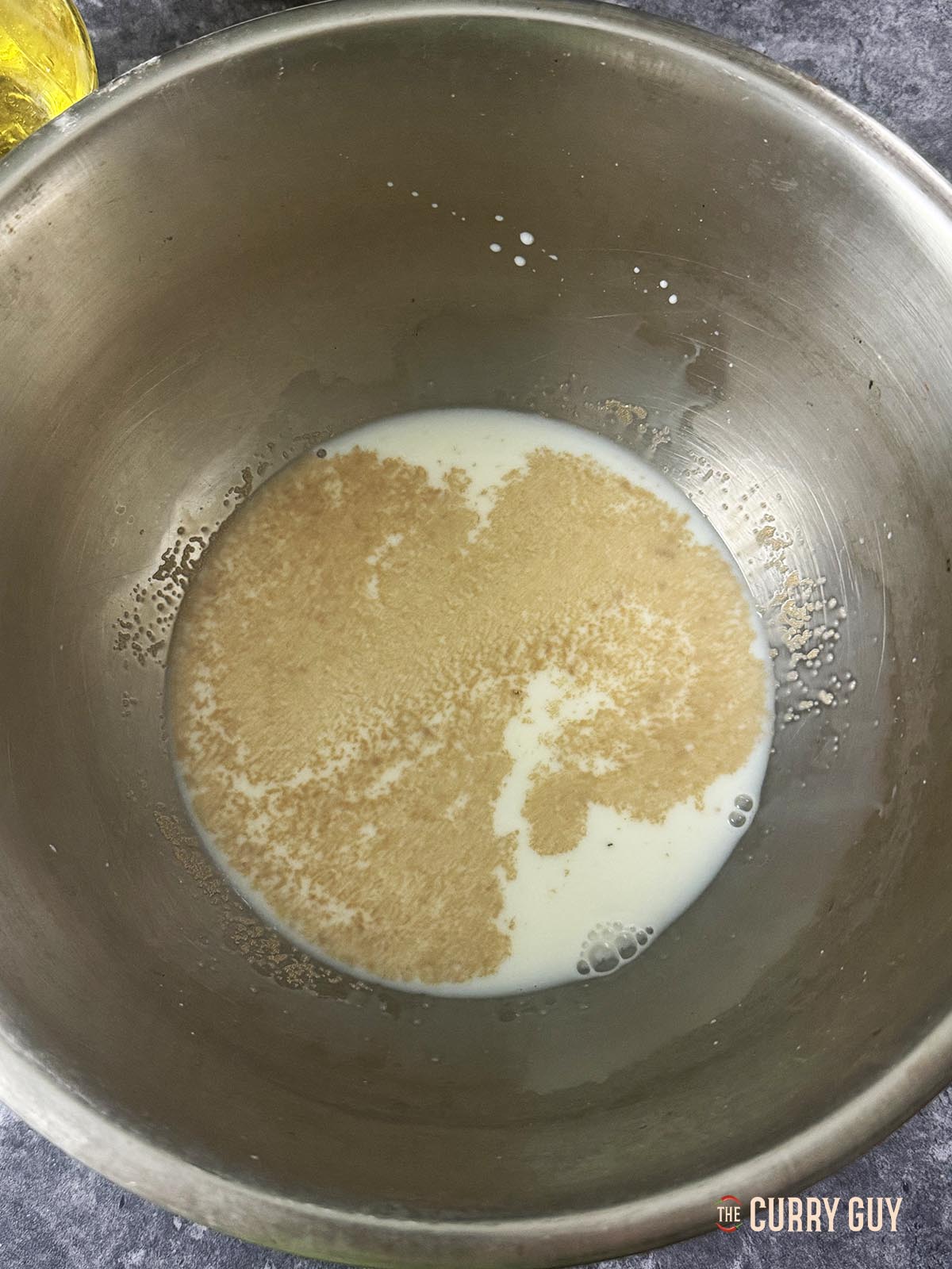 Mixing the yeast, sugar, oil and hand-hot milk and water in a mixing bowl.