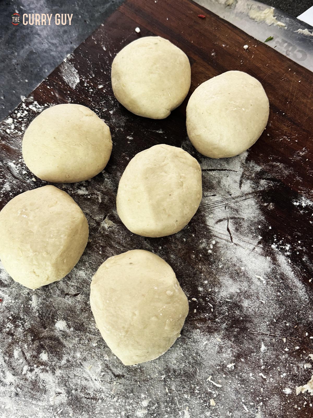 The large dough ball divided into six smaller balls.
