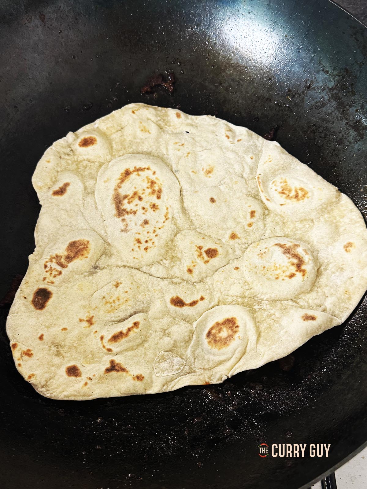 Pressing a lavesh bread into the meat and sauce to soak up some of the sauce and oil.
