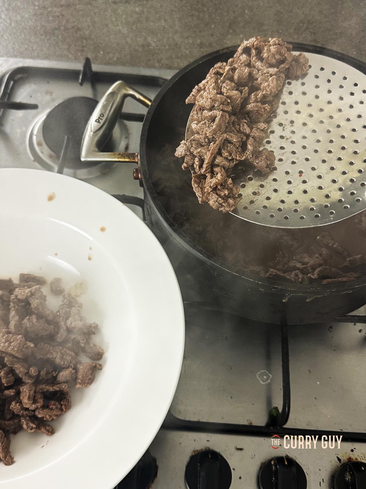 Transferring the braised beef to a plate and retaining the cooking liquid.