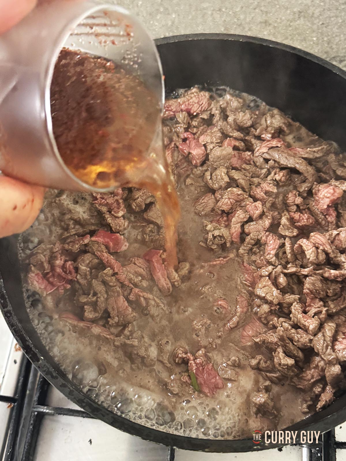 Pouring spiced water over the cooking meat.