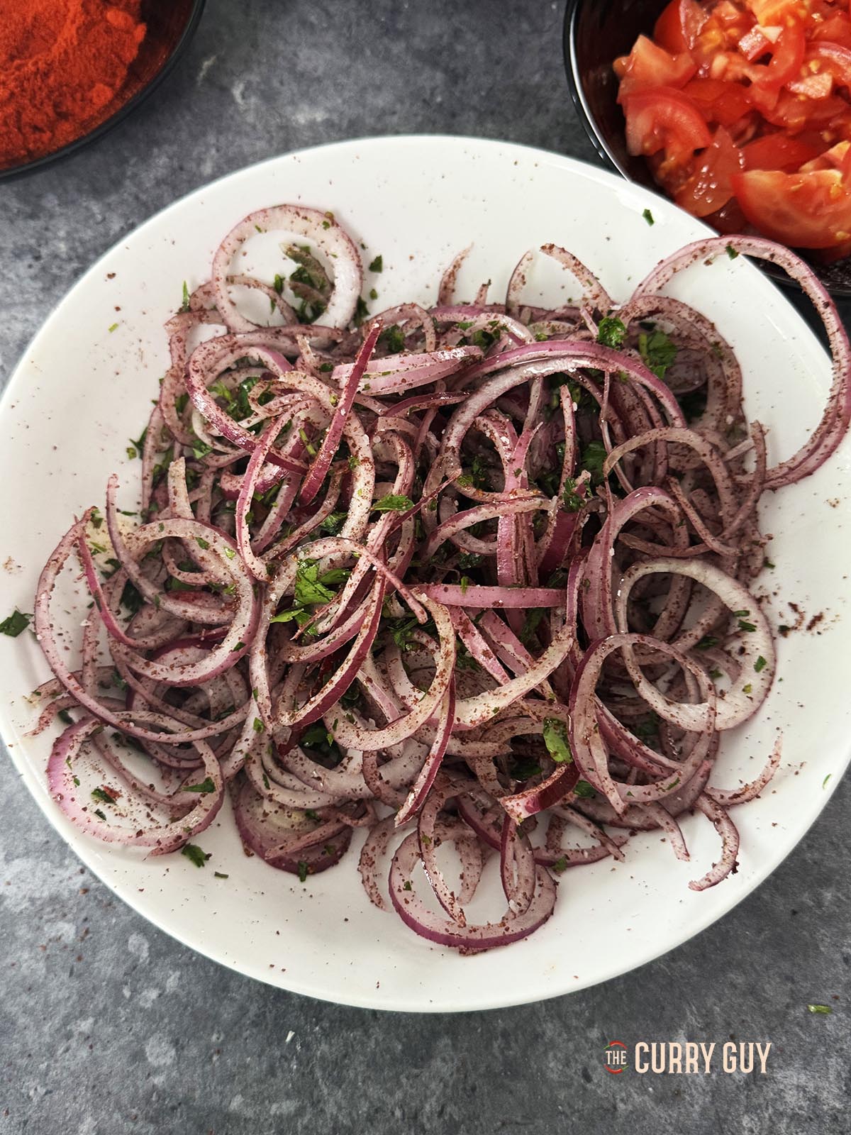 Mixing the salad ingredients. Sliced onions, sumac, salt, parsley and olive oil.