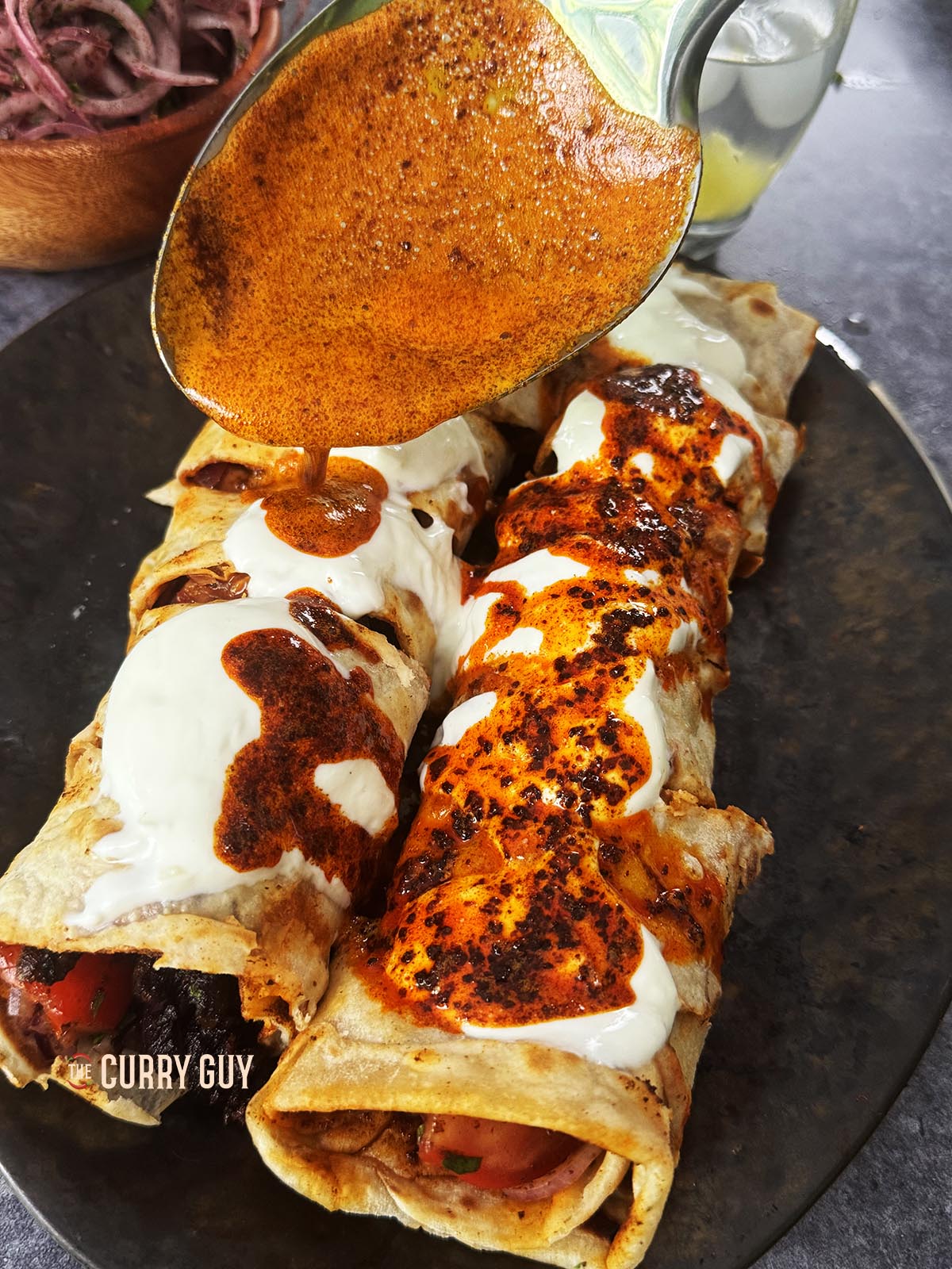 Drizzling the spiced oil over the yoghurt tantuni at the table. 