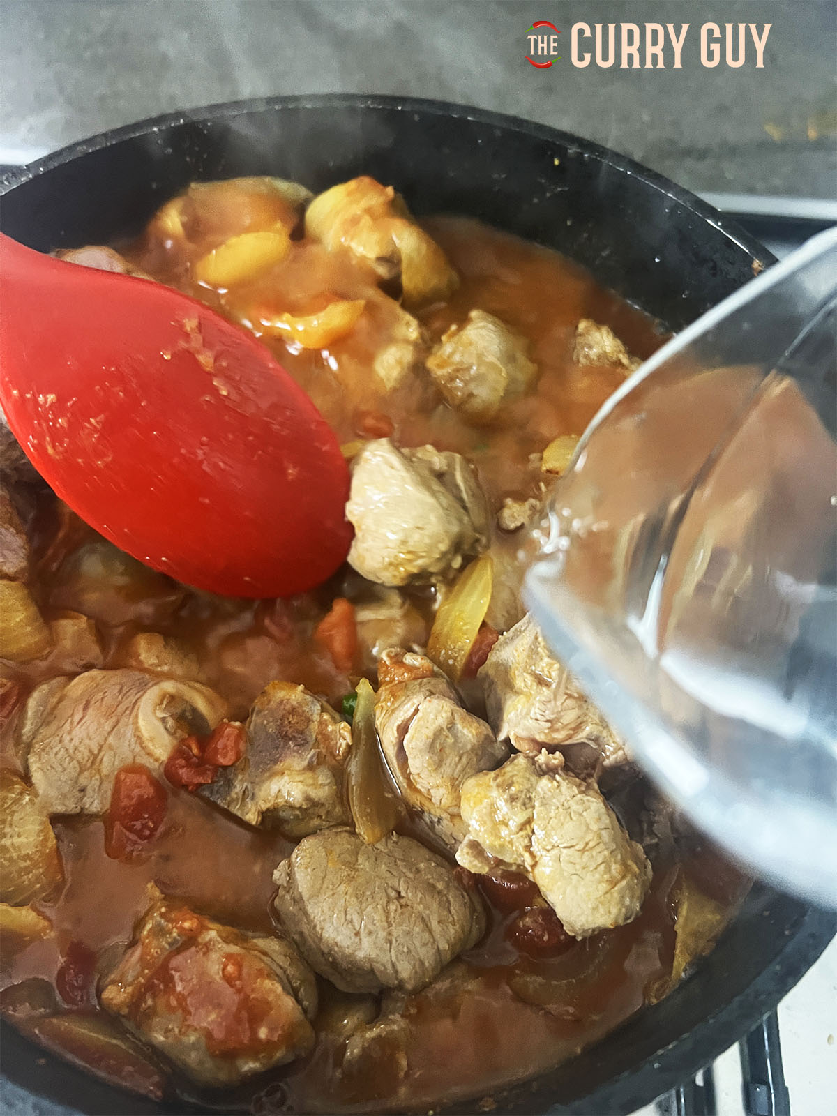 Adding water to the curry to cover the meat.
