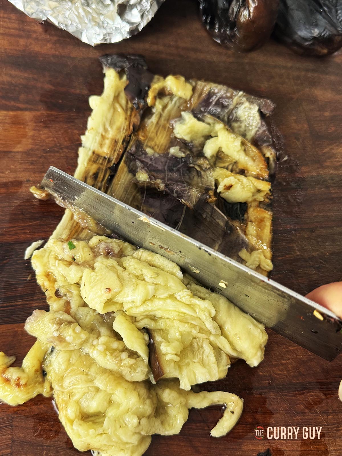 Scooping the flesh out of a cooked aubergine.