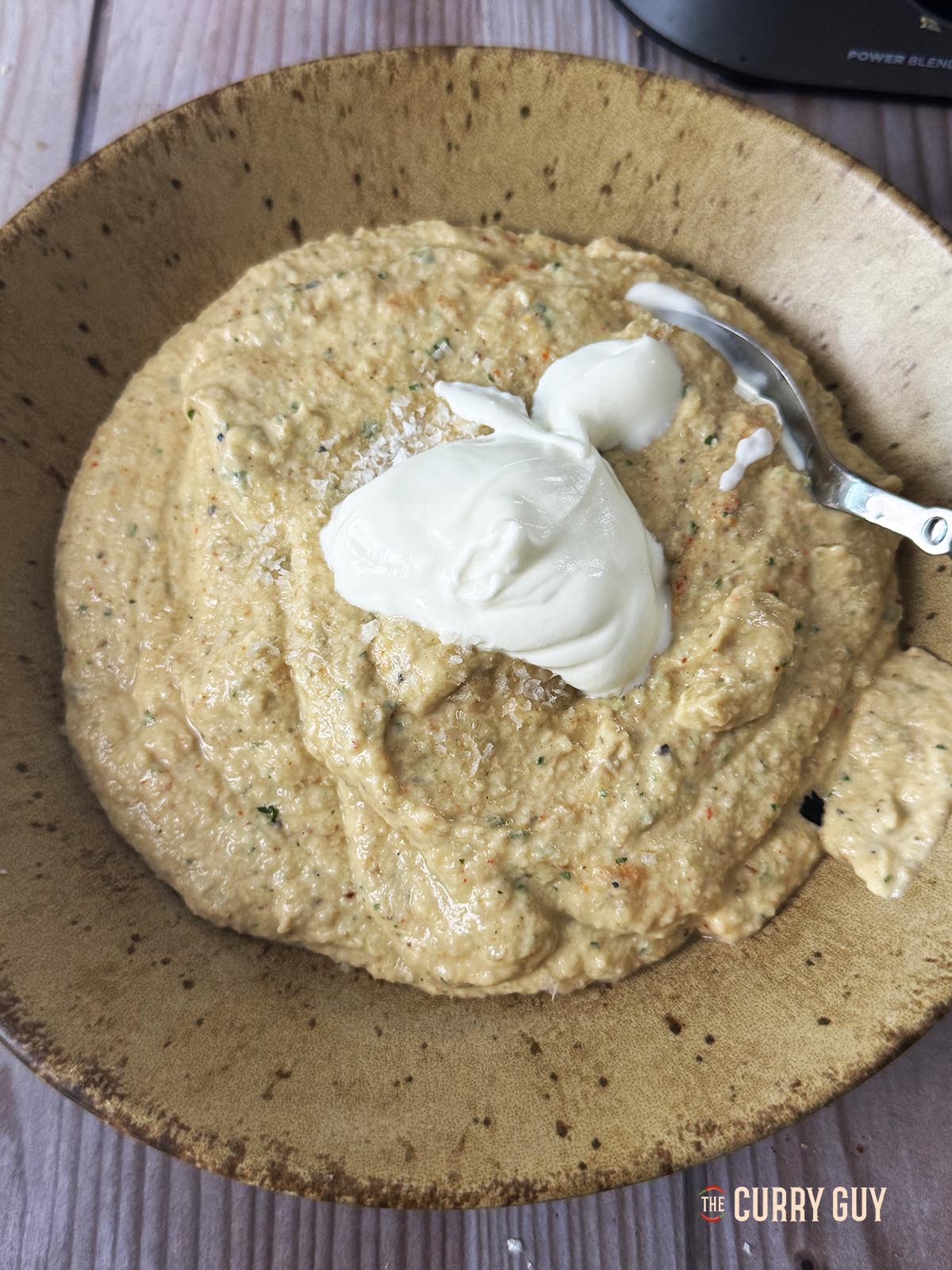 Adding yoghurt to the blended aubergine and spices. 