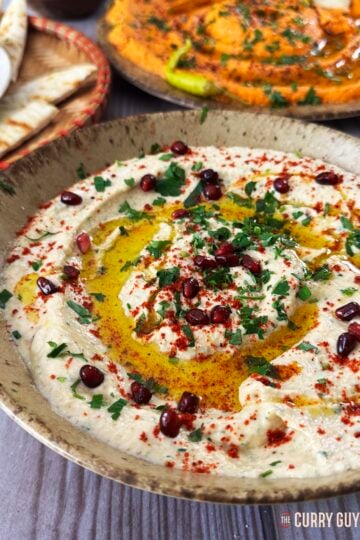 Baba ganoush in a serving bowl garnished with pomegranate seeds, olive oil and aleppo chilli flakes.
