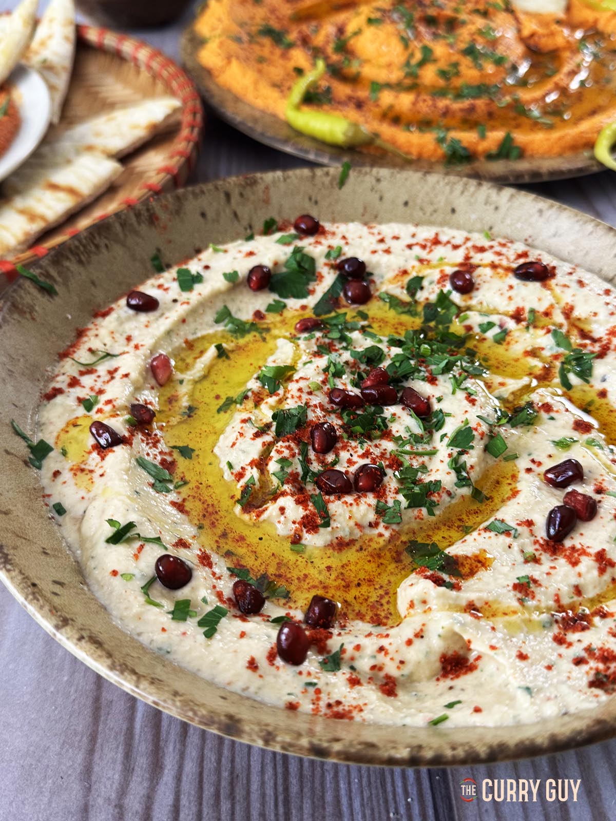Baba ganoush in a serving bowl garnished with pomegranate seeds, olive oil and aleppo chilli flakes.