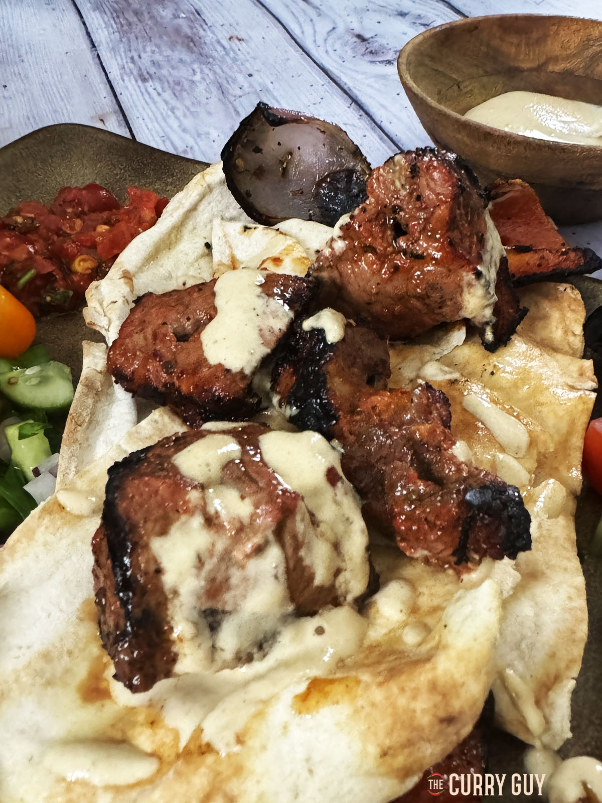 The beef kabobs served at the table with tahini sauce and lavish bread.