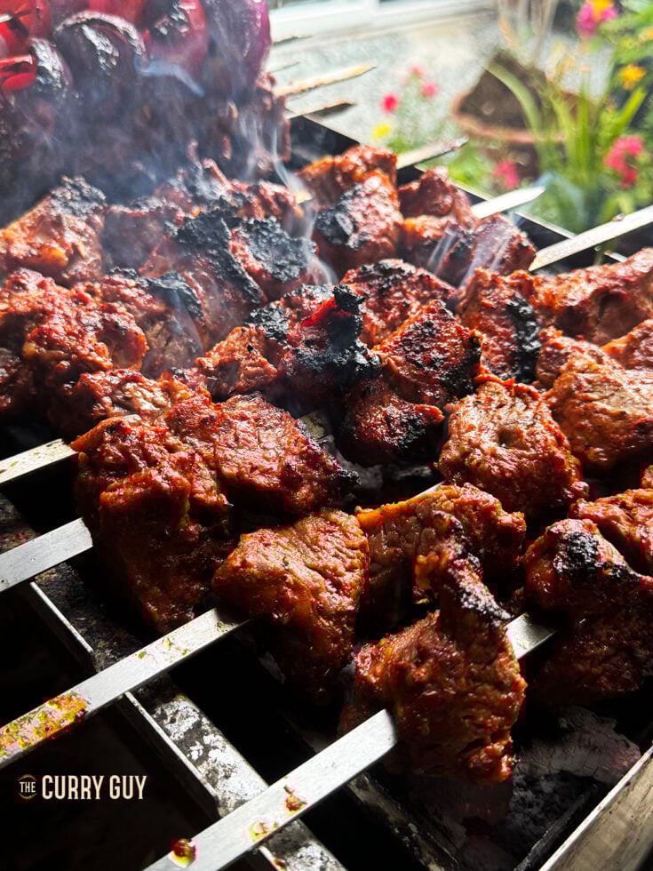 Beef shish kabobs cooking over hot coals.