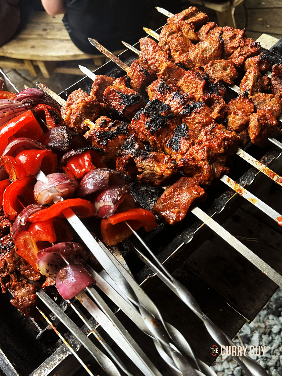 The meat and vegetables cooking on skewers over the hot coals.