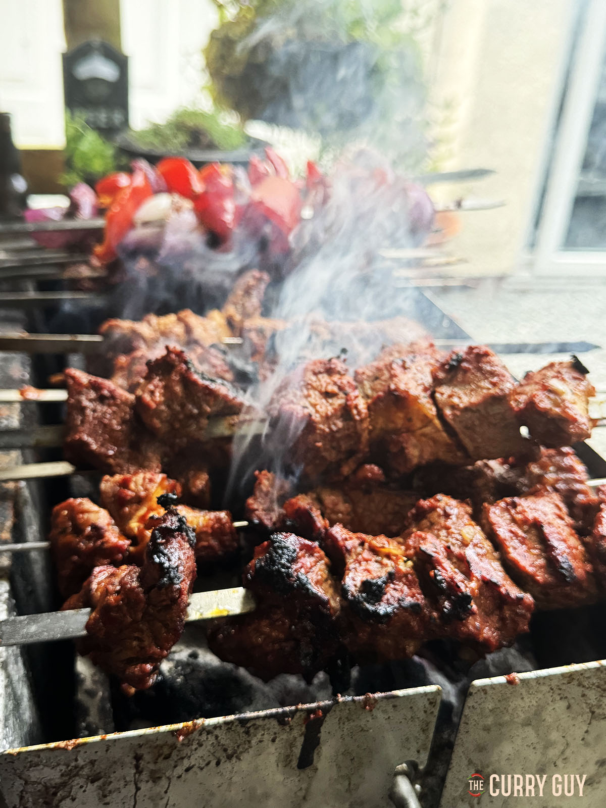 Grilling the meat and vegetable skewers over the fire.