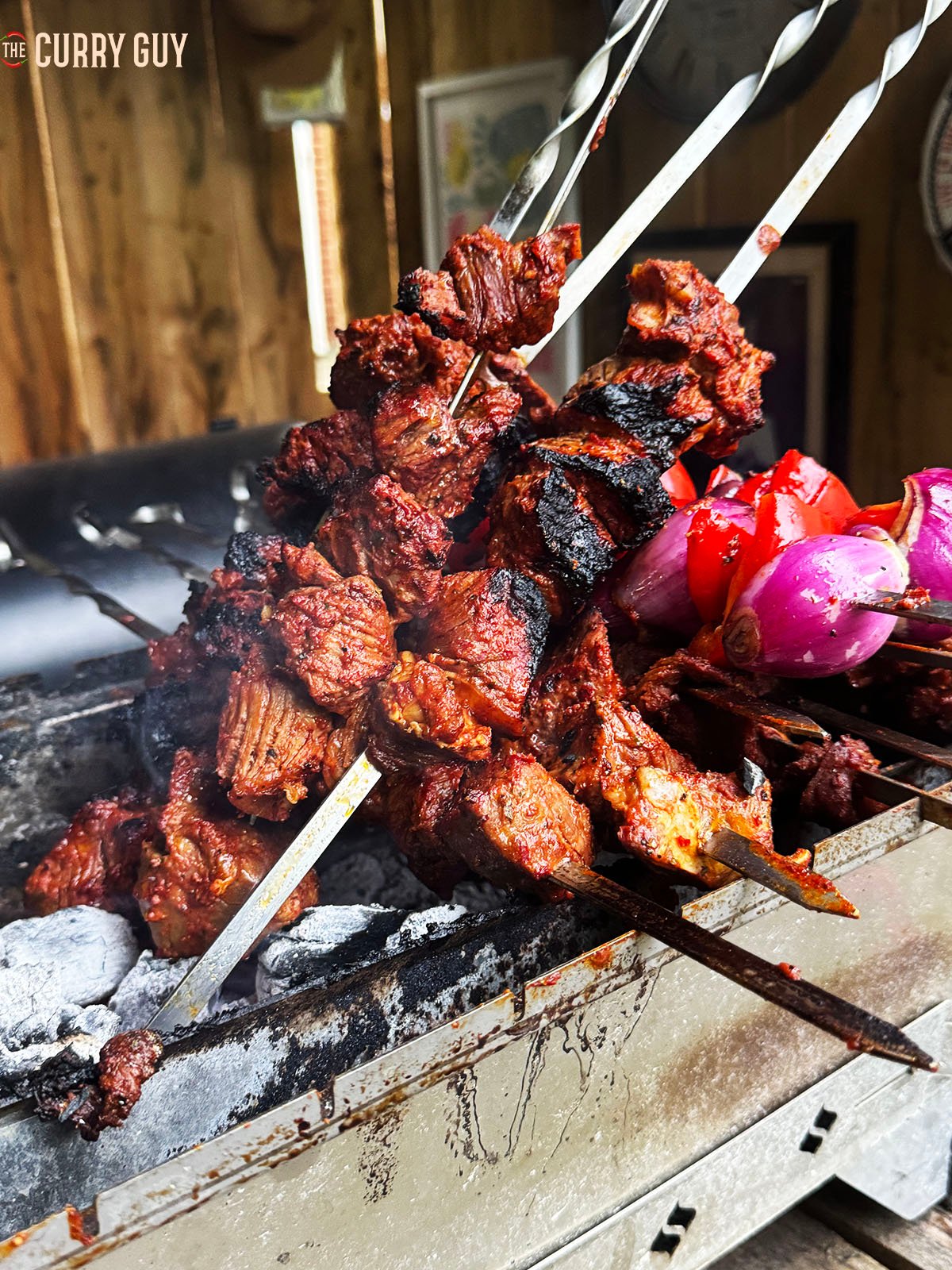 Beef shish kabobs smoking on skewers over hot coals.