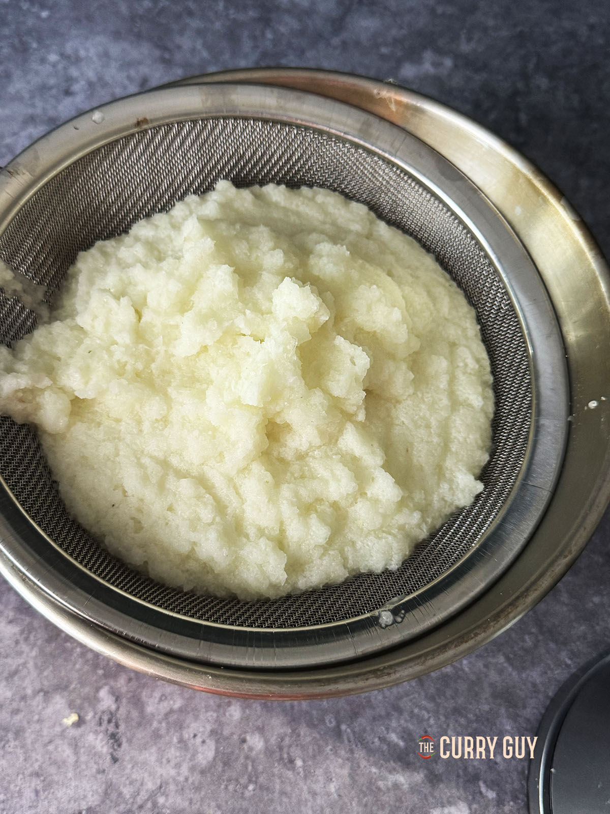 Running the onion paste through a fine mesh strainer to get the juice out.