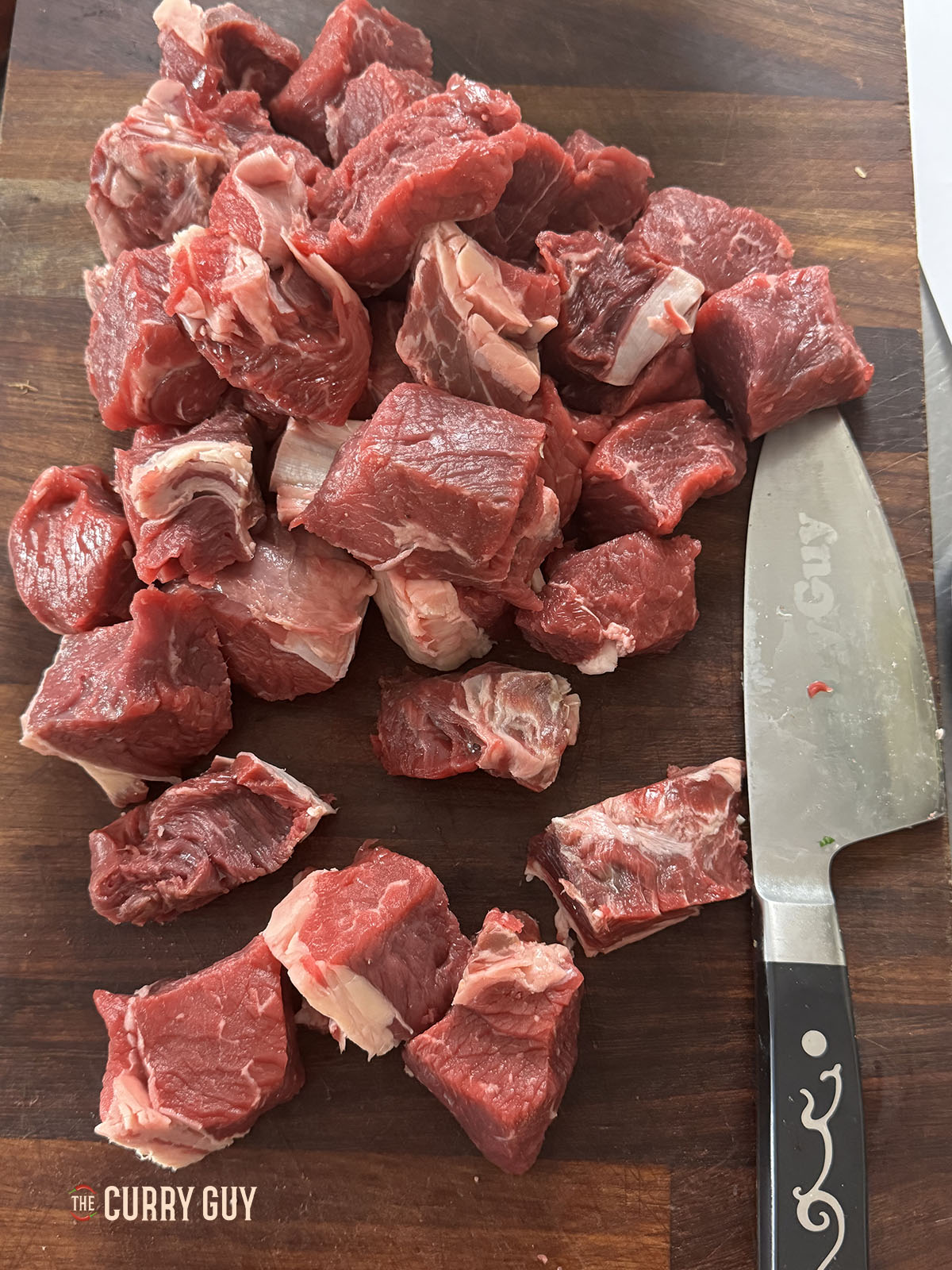 The beef cut into large bite sized pieces on a cutting board.