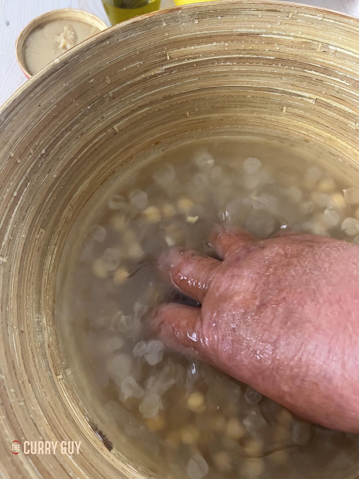 Squeesing the skins off the chickpeas in a bowl of water. 