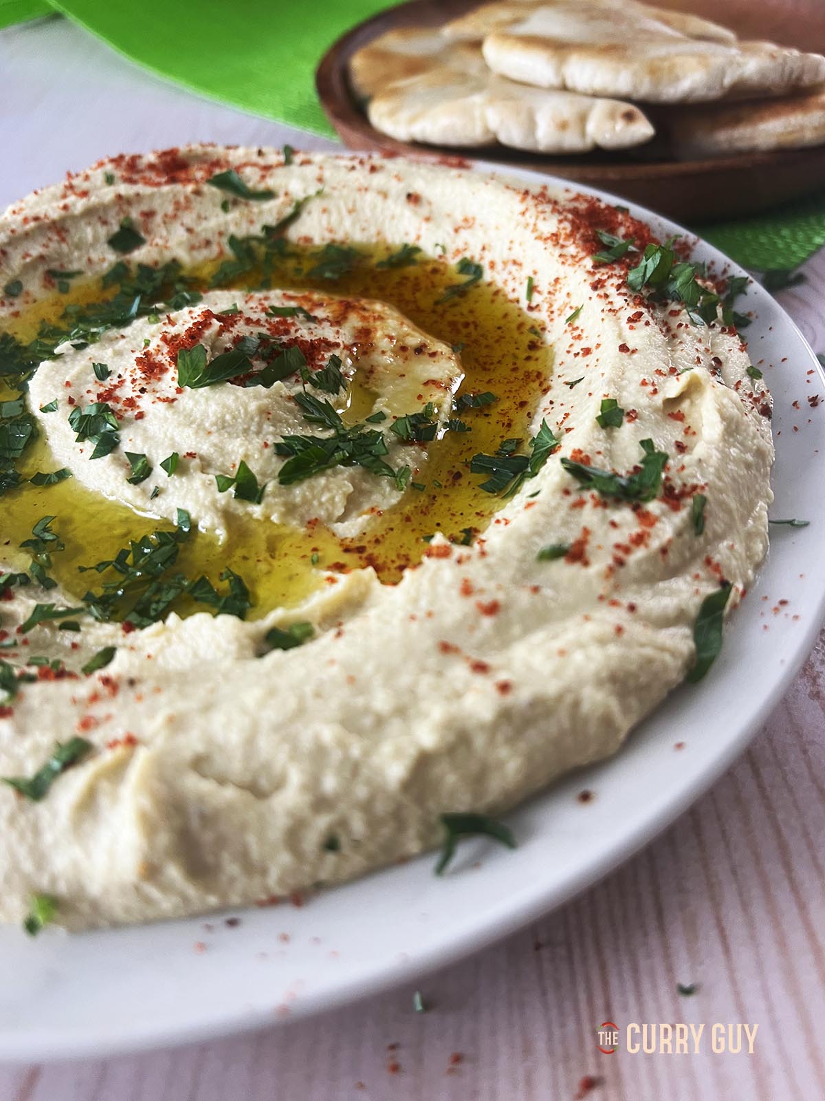 Hummus garnished with olive oil, parsley and aleppo chilli flakes.
