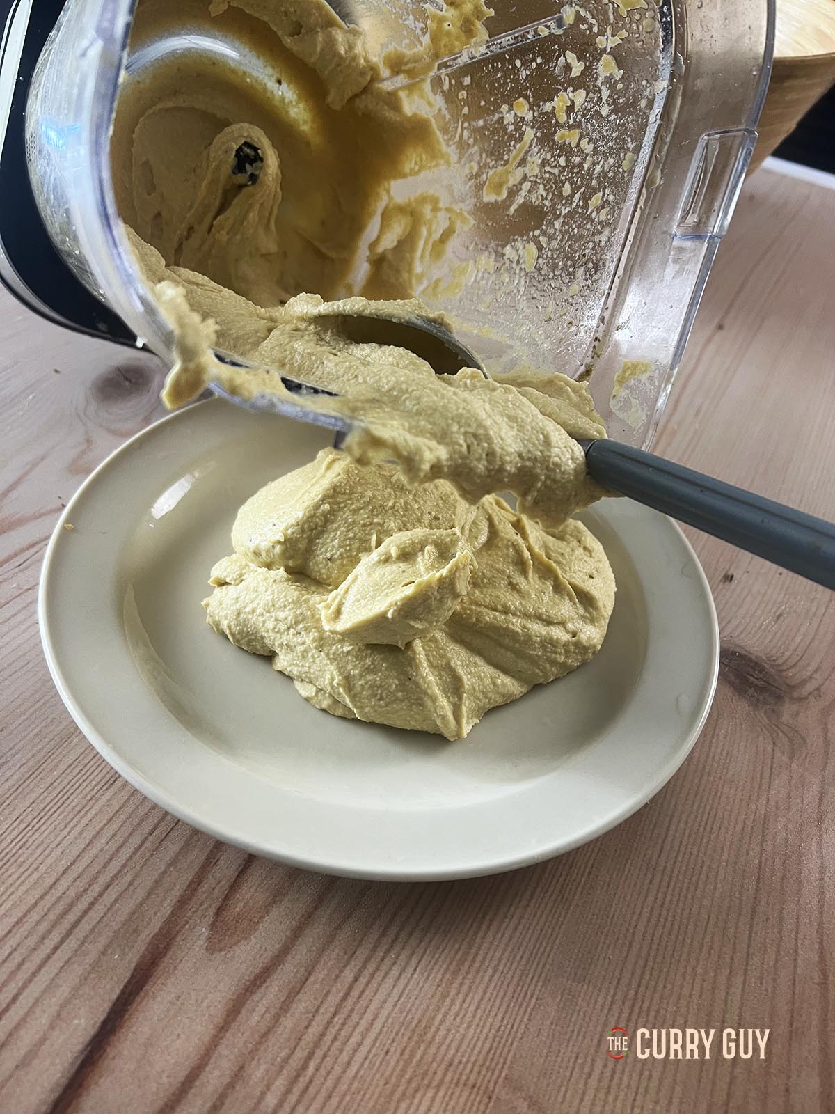 Transferring the smooth hummus to a serving plate. 