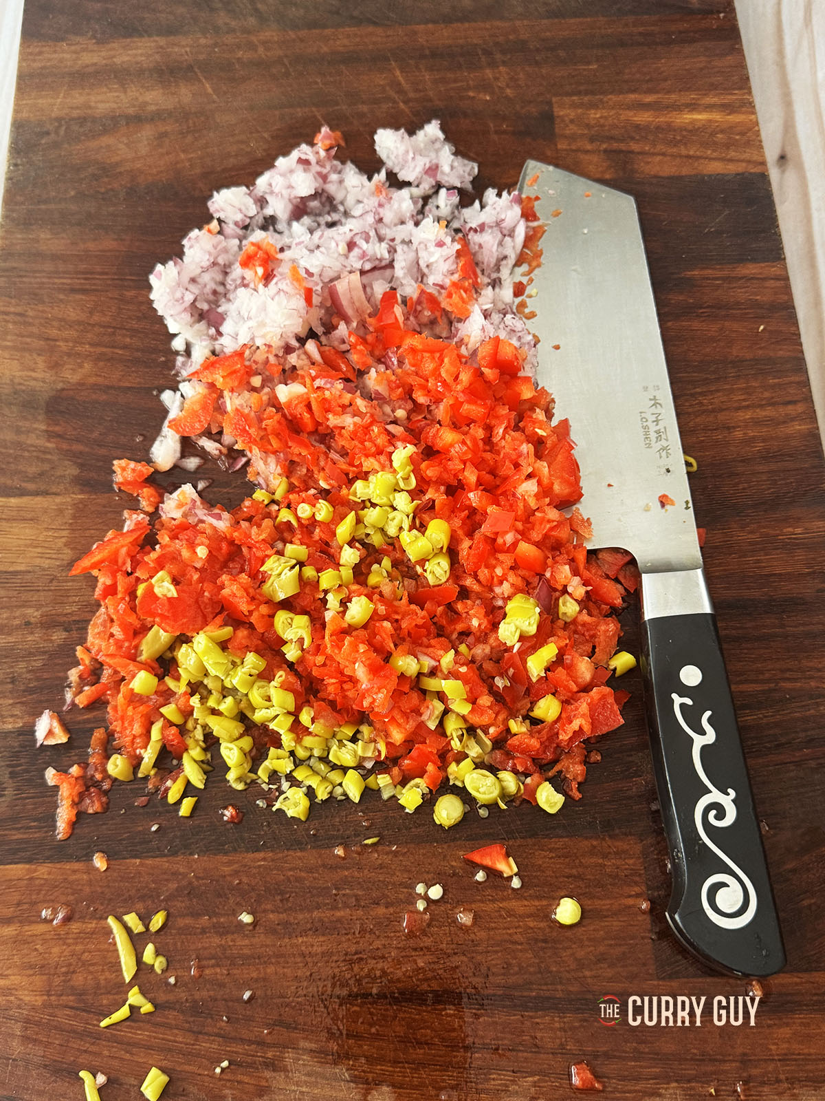 Finely chopping the onion, bell pepper and wax chillies.
