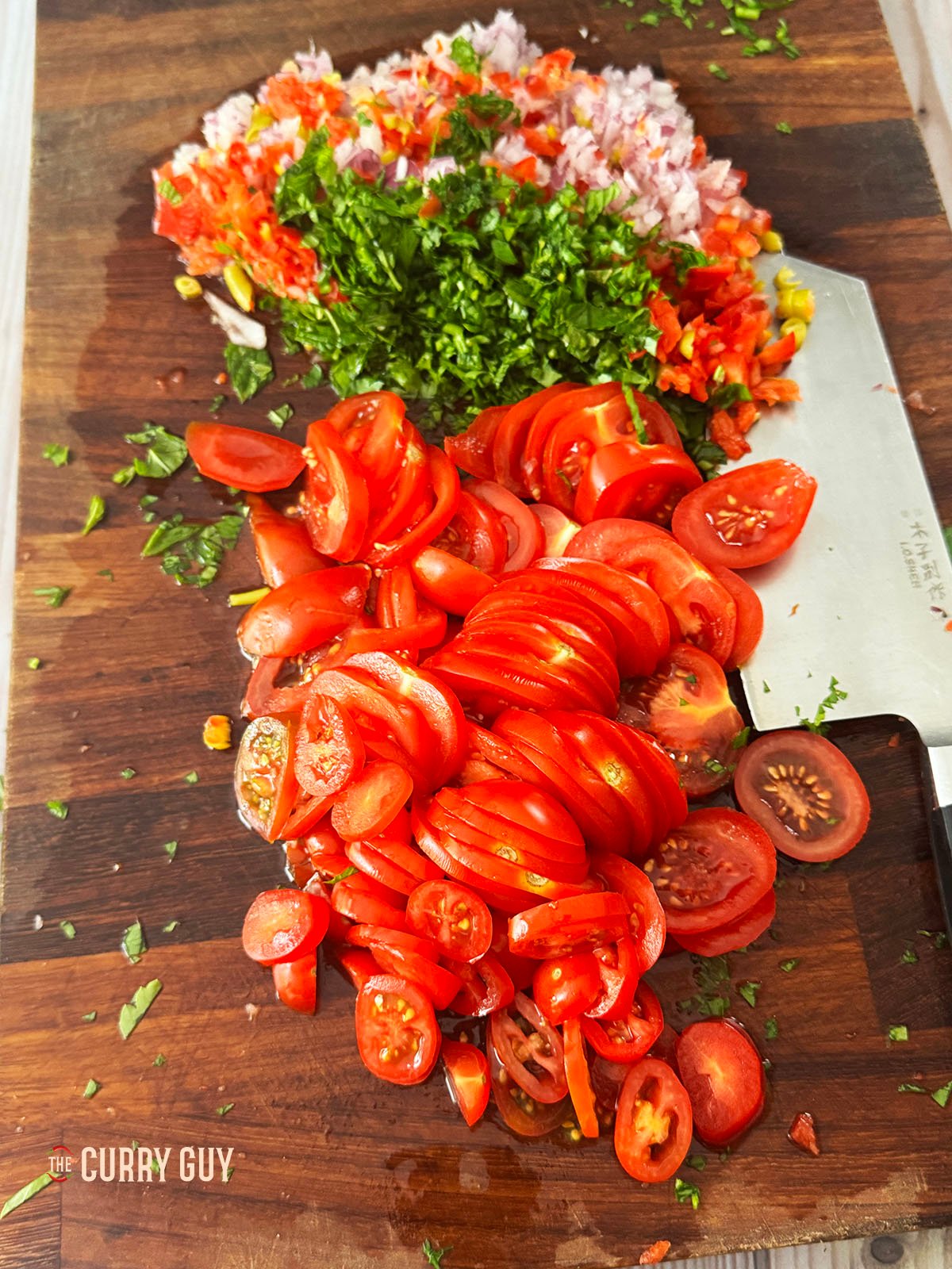 The tomatoes thinly sliced next to the other ezme ingredients. 