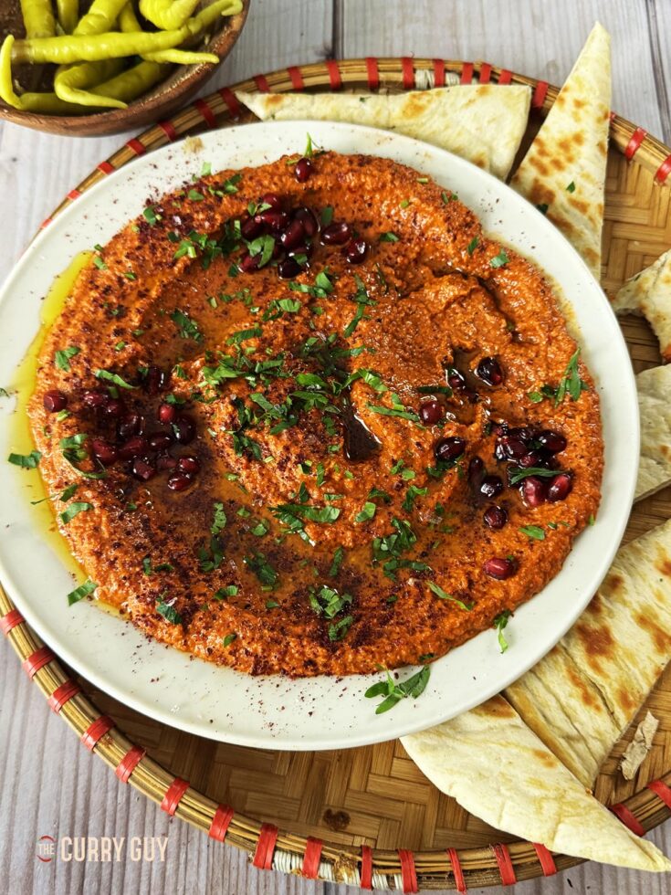 muhammara in a serving dish with pitas.