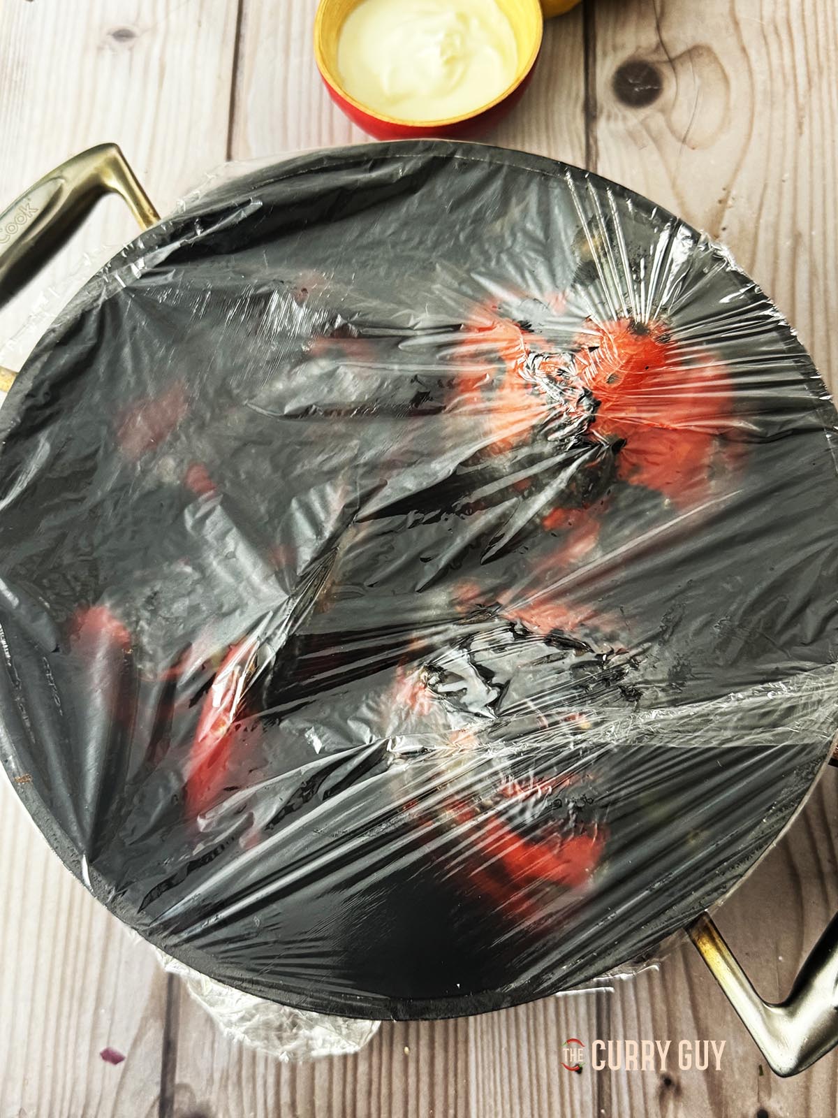 Covering the peppers with clingfilm to cool and loosen the skins.