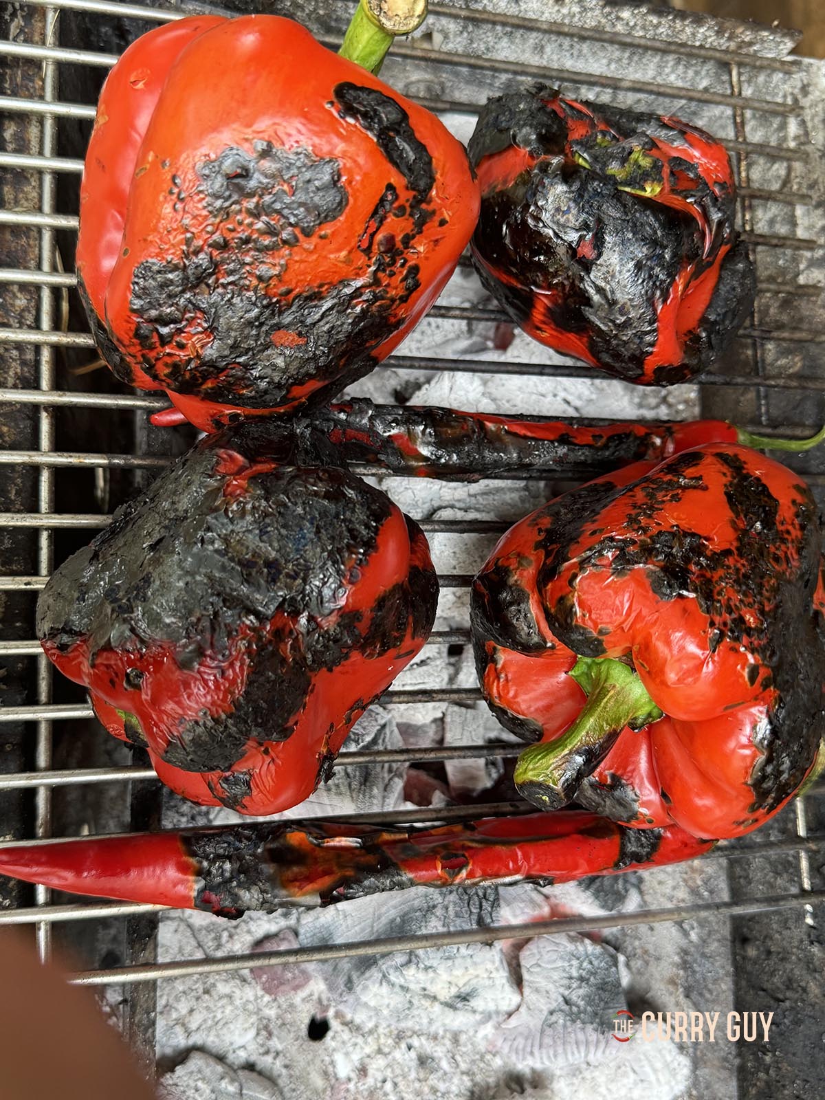 Roasting the peppers over hot coals to blacken them.