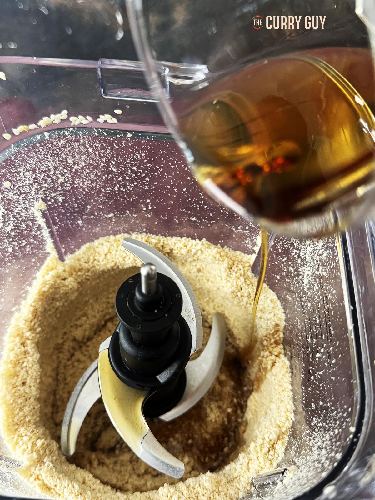 Adding sesame oil to the sesame seeds to blend.