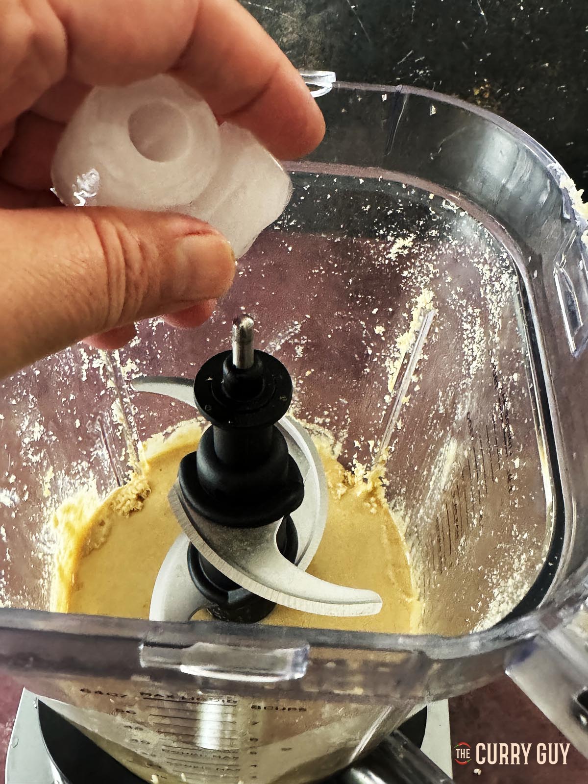 Adding ice cubes to the blended sesame seeds.
