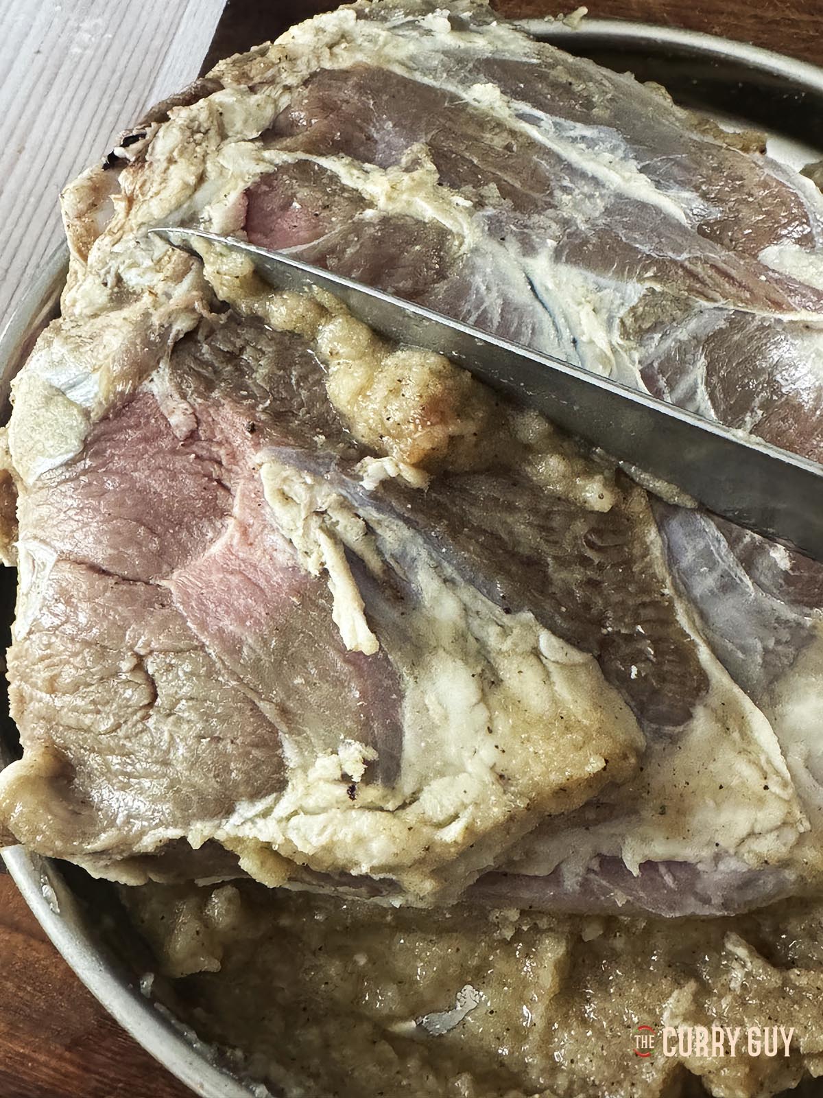 Scraping the onion marinade off the lamb leg. 