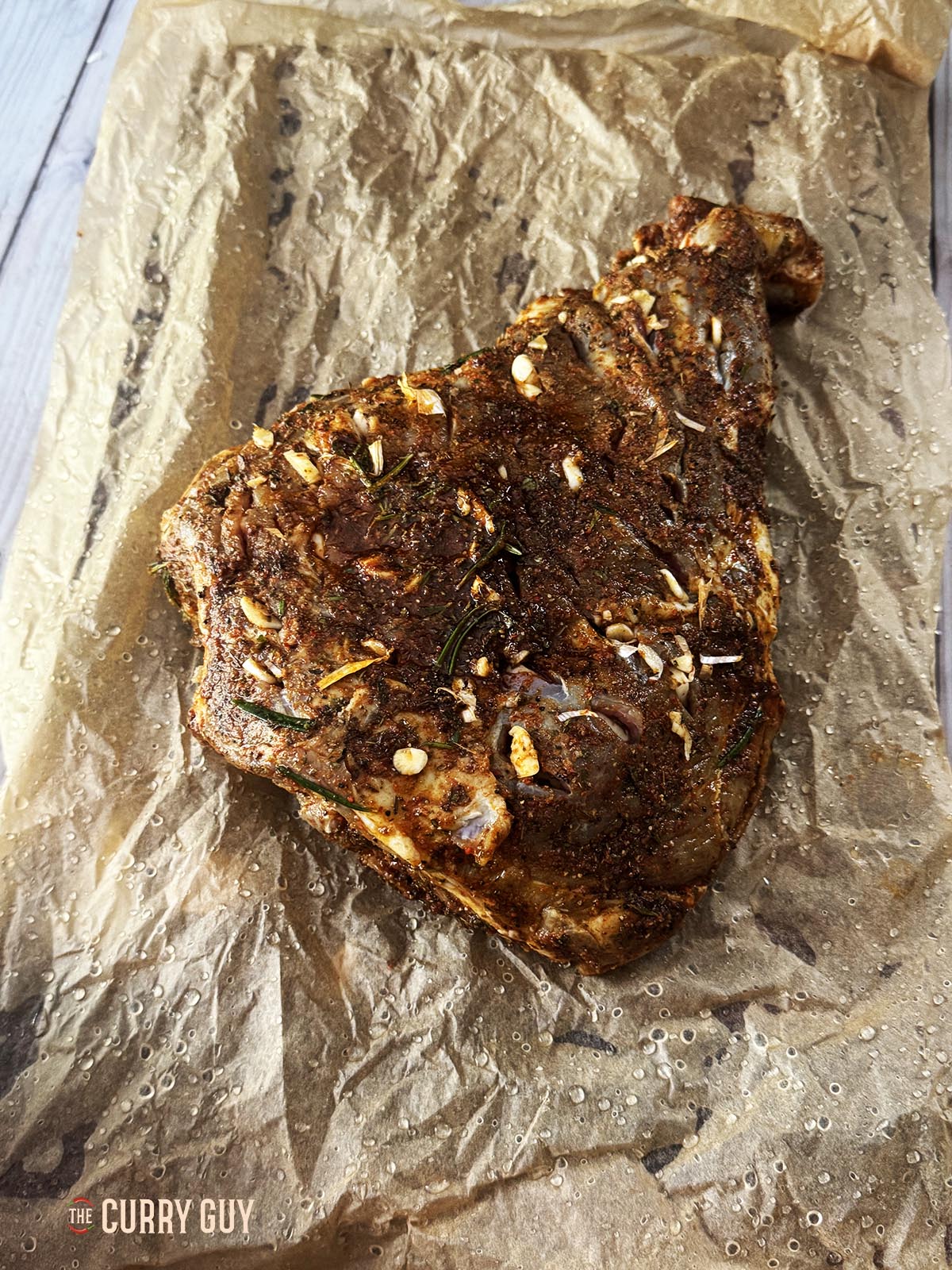 The lamb leg on a piece of parchment paper, ready for wrapping.