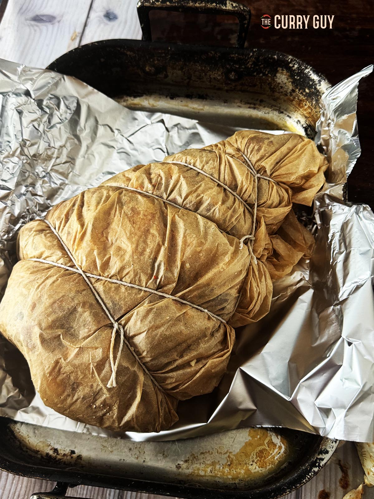 The lamb leg wrapped in parchment paper and tied.