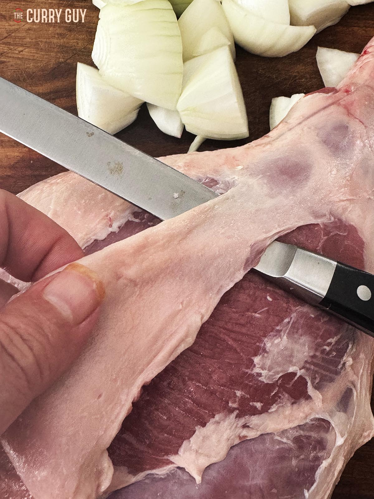 Trimming the meat fat and silver skin off the leg of lamb.