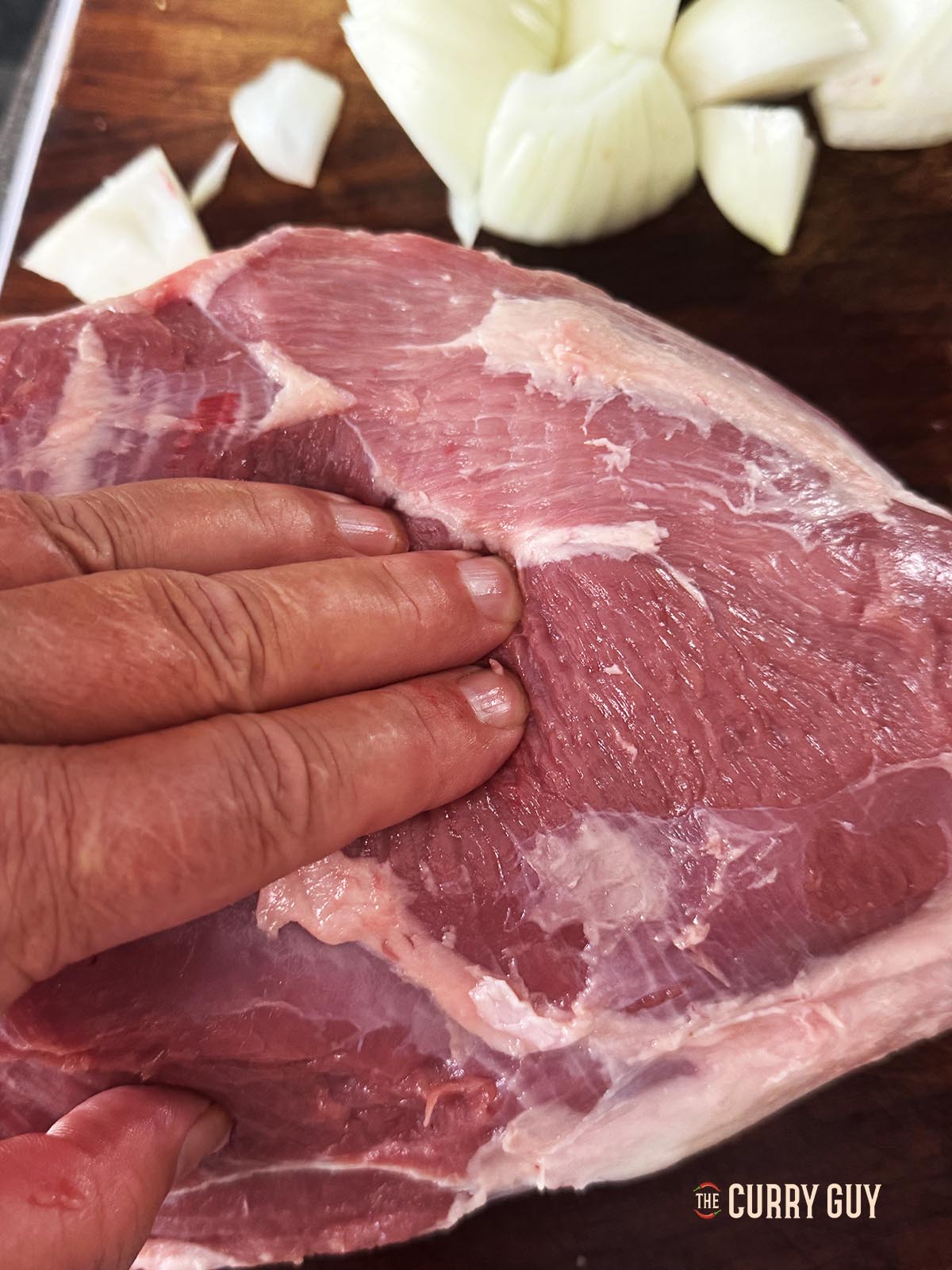 Pressing the meat to show that it is not yet tender. 