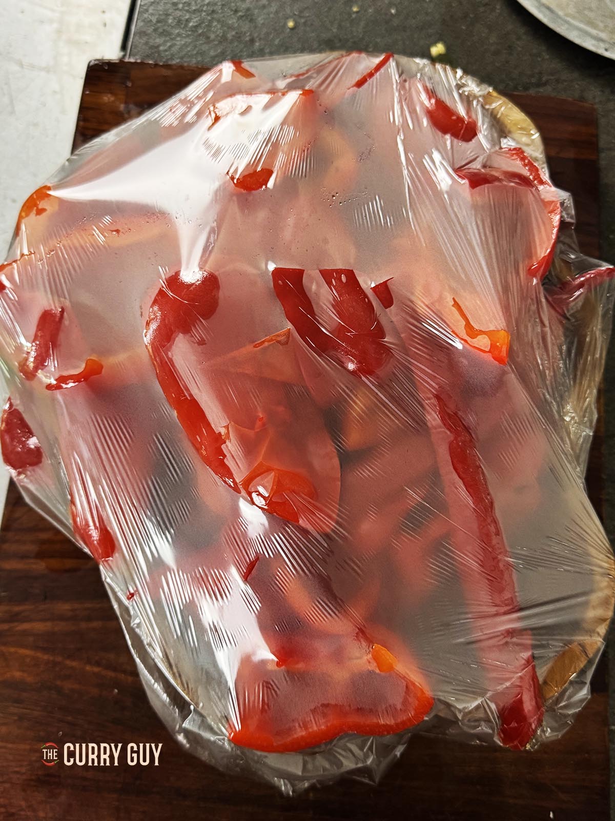 Letting the peppers cool under plastic wrap to make it easier to peel off the skins.