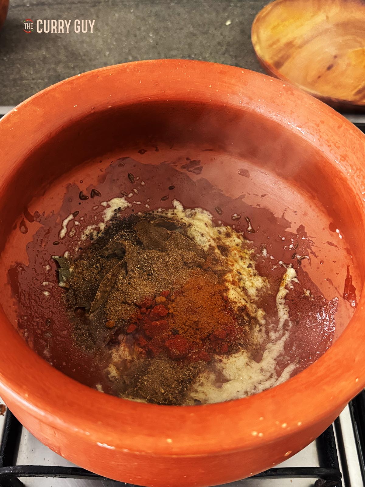 Adding the ground spices to the pan and stirring them into the other ingredients. 