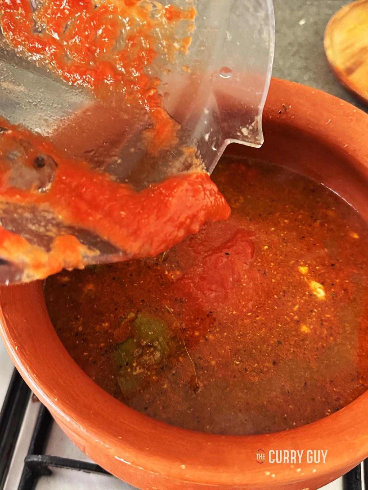 Adding the blended tomatoes to the pan.