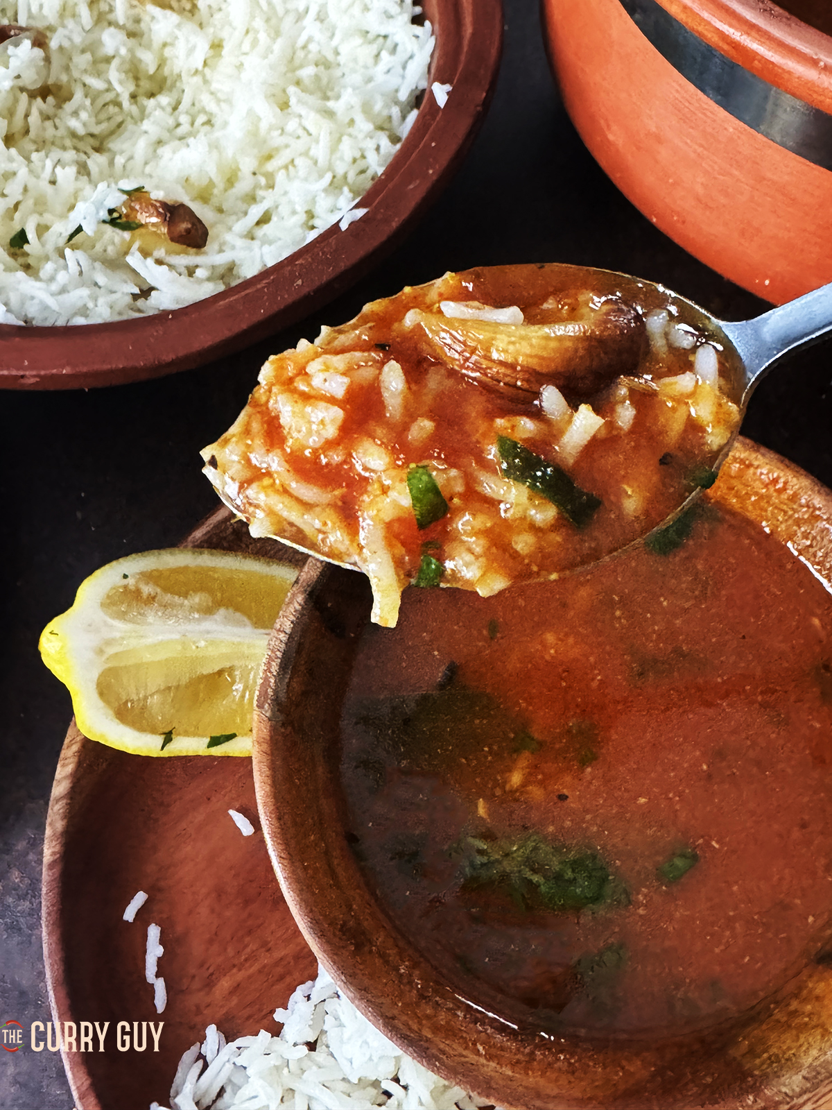 Tomato shorba with rice and roasted garlic on a spoon. 
