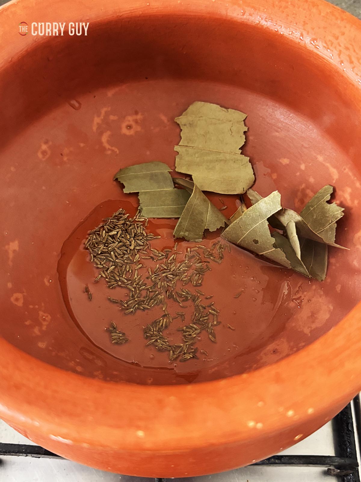 Infusing the cumin seeds and bay leaves in oil.