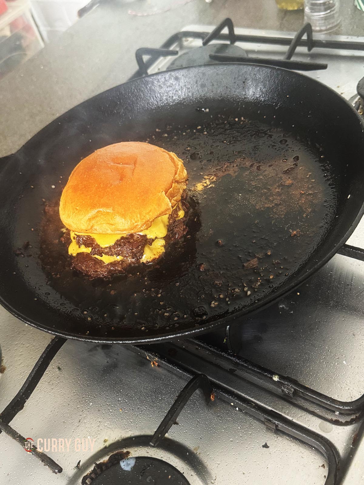 Adding the top bun to the burger patties.