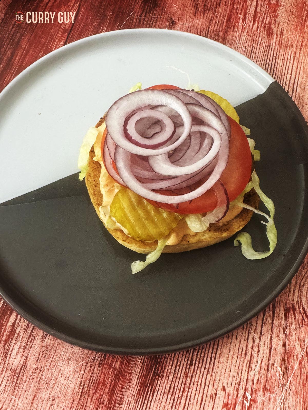 Adding sliced onion and tomato to the bottom buns.