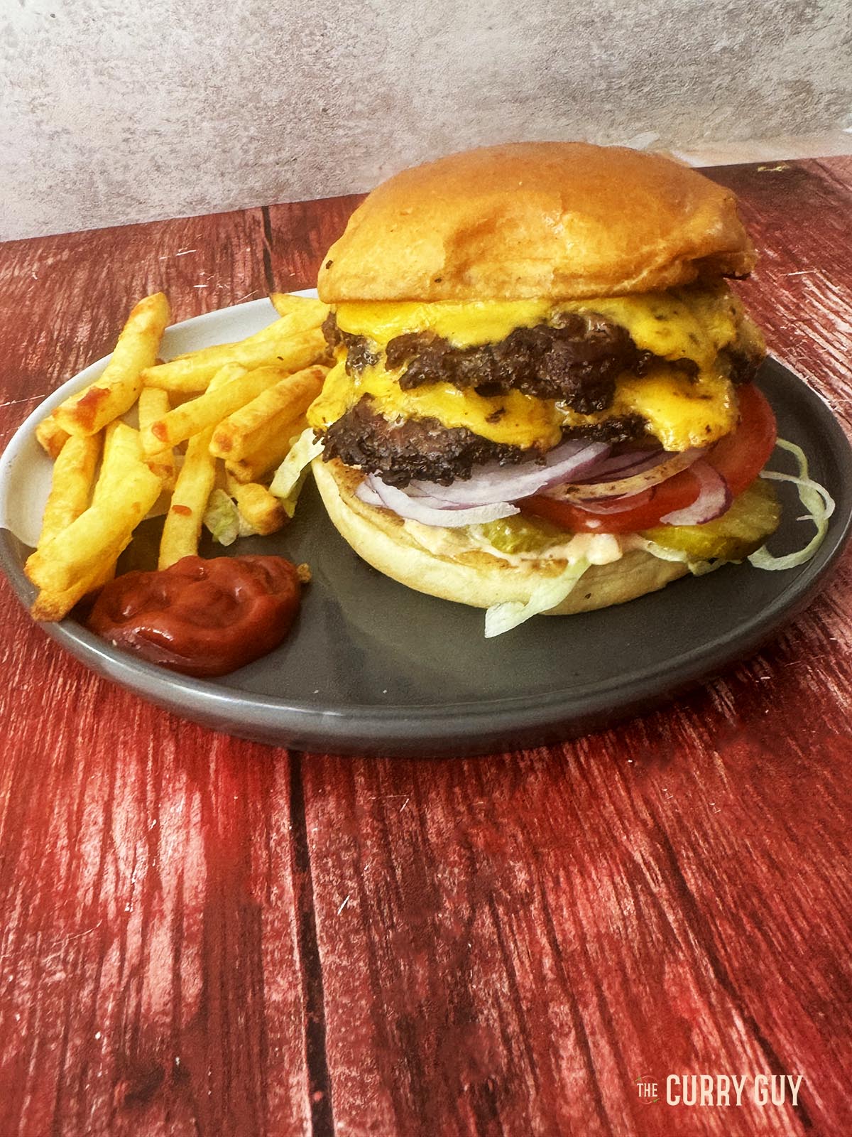 The smash burger served on a plate with french fries.