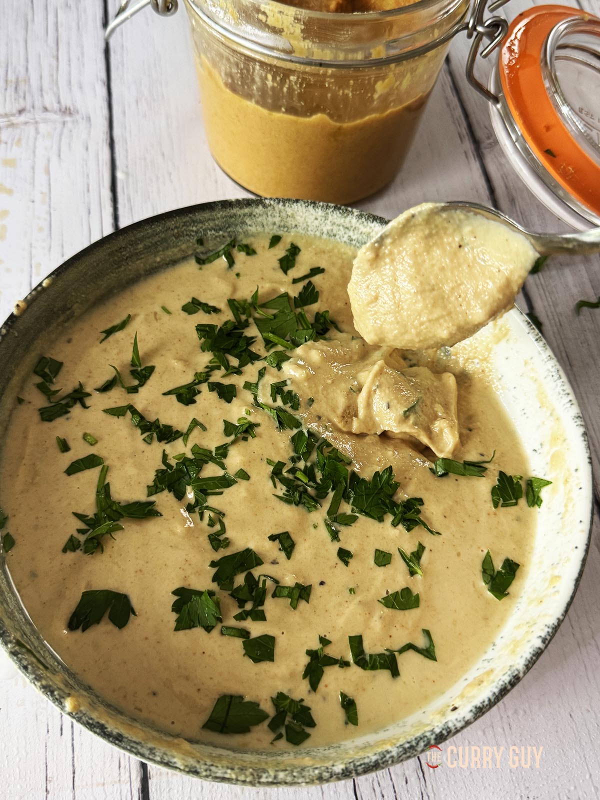 Tahini sauce in a serving bowl. A spoon showing the thick consistency of the sauce.