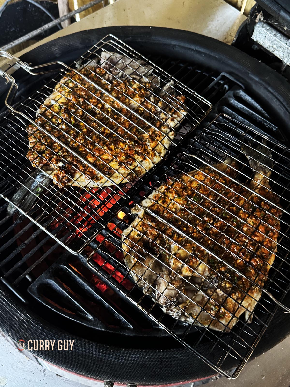 Grilling the fish in the fish basket over hot charcoal.