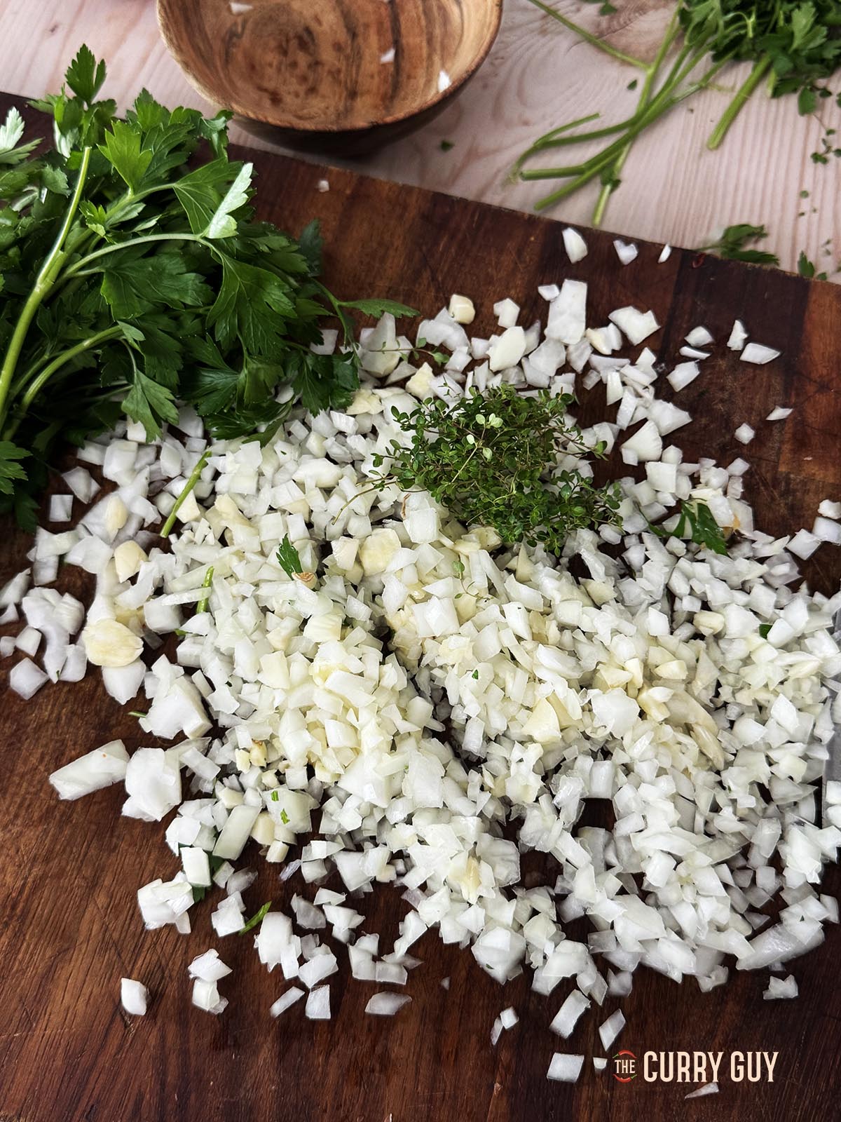 Finely chopped garlic and onion on a cutting board.