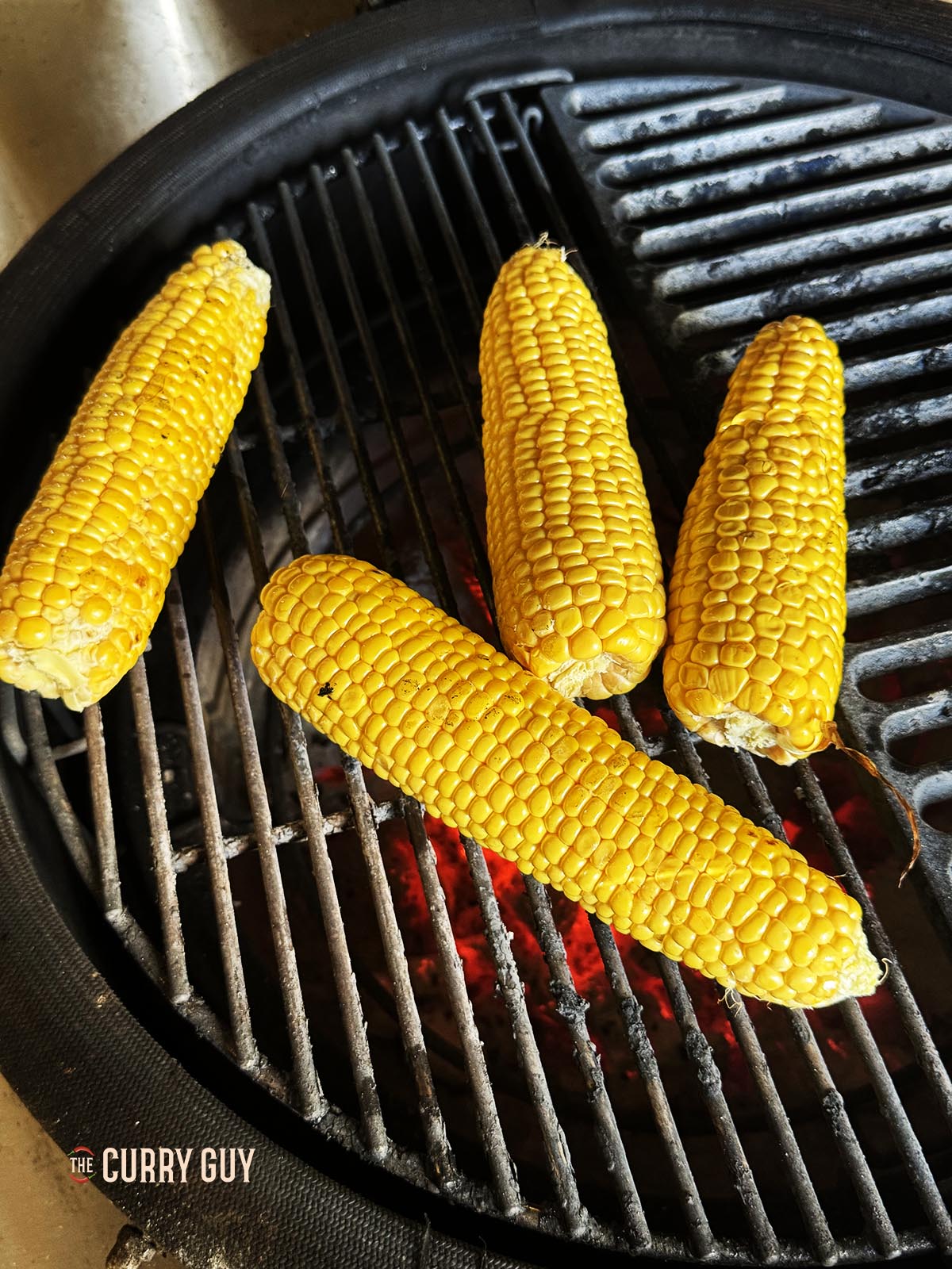 The corn cooking over charcoal.